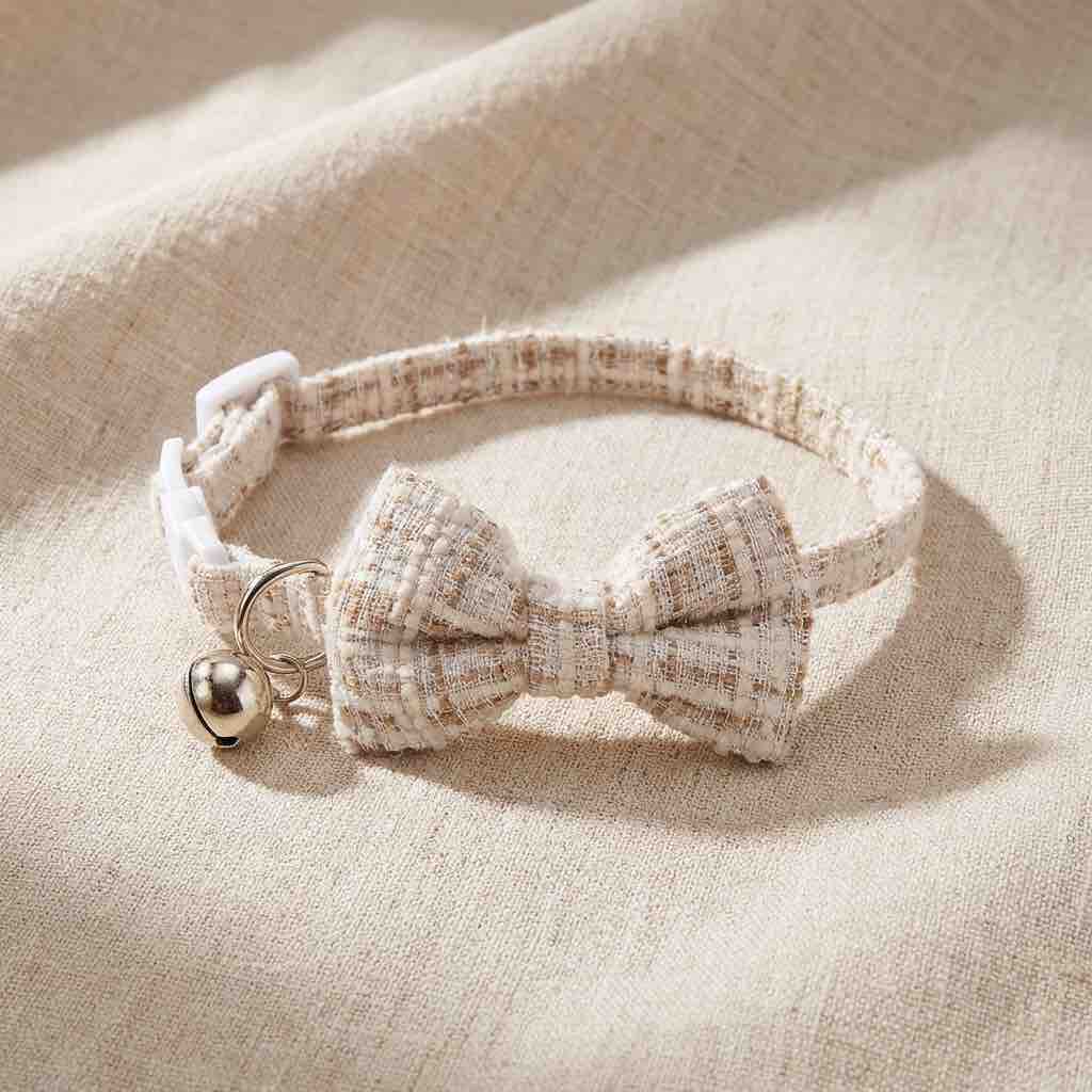 un noeud papillon beige rayé pour chat avec un fermoir anti-étranglement